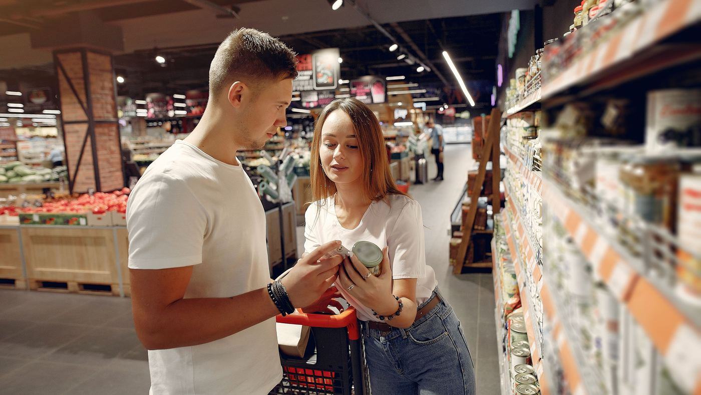 Two shoppers in a supermarket reading the label on a jar